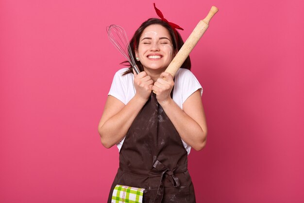 Heureuse femme au foyer ou chef boulanger portant un tablier de cuisine tenant un rouleau à pâtisserie