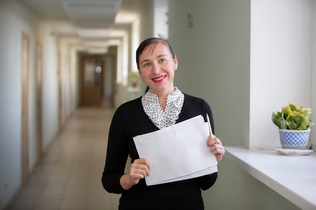 Heureuse femme au travail Employée dans le couloir avec un morceau de papier