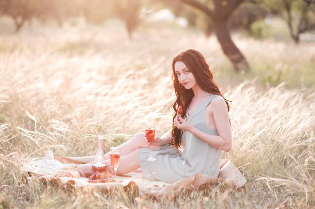 Heureuse femme ayant un pique-nique romantique dans le pré