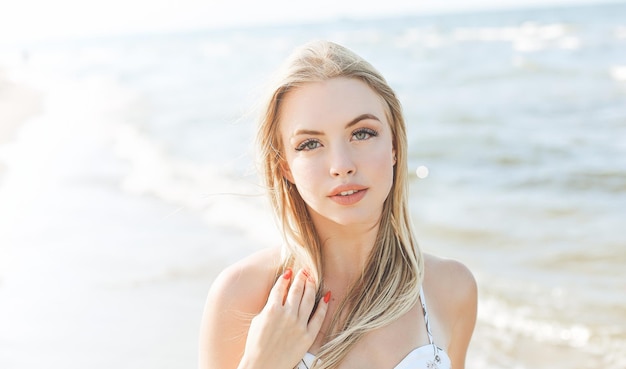 Heureuse femme blonde dans le bonheur gratuit sur la plage de l'océan debout tout droit et posant.