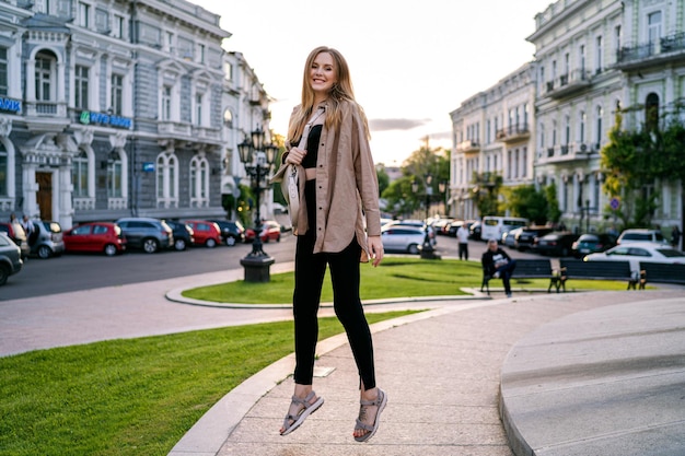 Photo heureuse femme blonde élégante posant dans la rue voyager en europe l'été