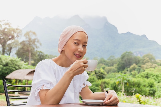 Heureuse femme buvant du café à l'extérieur avec vue sur la montagne en vacances