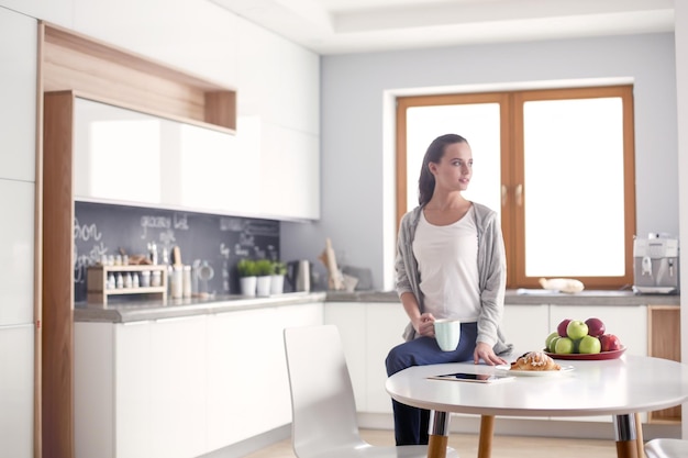 Heureuse femme buvant du thé dans la cuisine à la maison