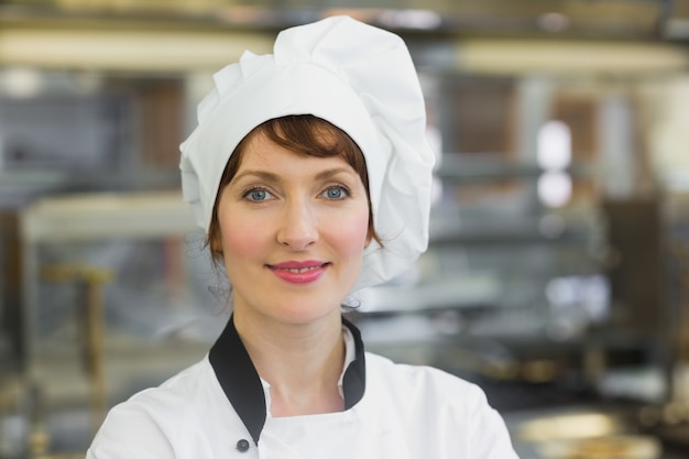 Heureuse femme chef posant dans une cuisine