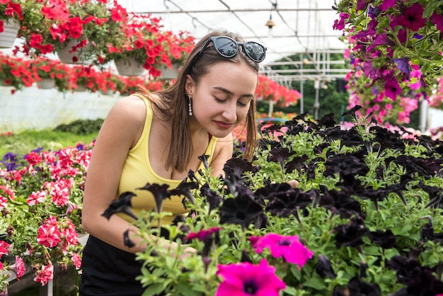 Heureuse femme choisit des fleurs dans une serre. Botanique