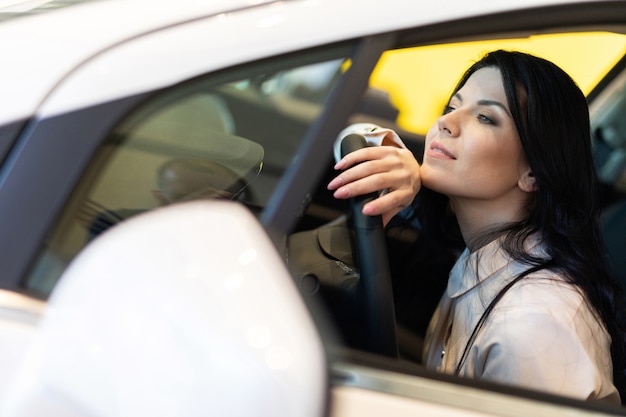 Heureuse femme client achetant une nouvelle voiture dans le centre de distribution