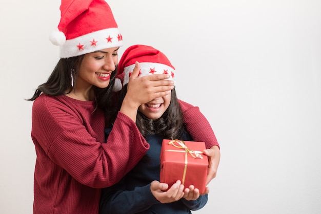 Heureuse femme couvrant les yeux et offrant un cadeau à sa petite fille.