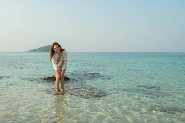 Heureuse femme debout les bras tendus sur la plage en mer