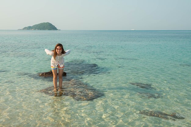 Heureuse femme debout les bras tendus sur la plage en mer