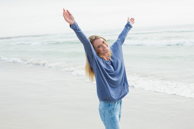 Heureuse femme debout avec les mains levées à la plage