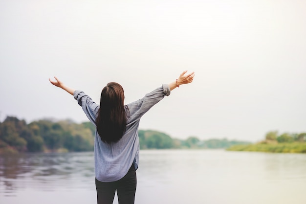 Heureuse femme debout près de la rivière. Levant les bras pour respirer l&#39;air frais