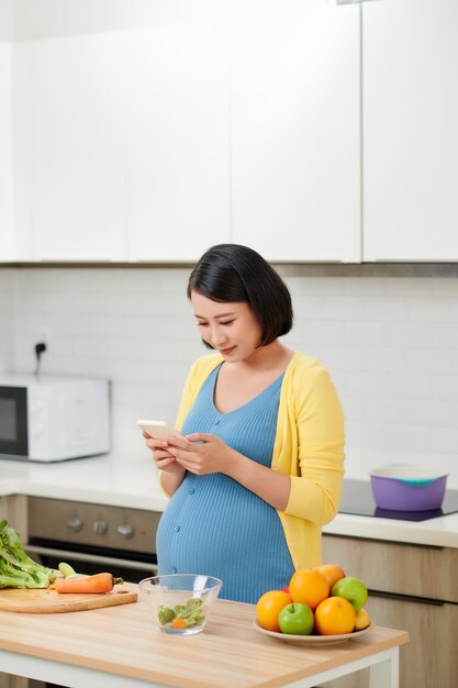 Heureuse femme enceinte à l'aide de l'enregistreur de commande vocale sur smartphone
