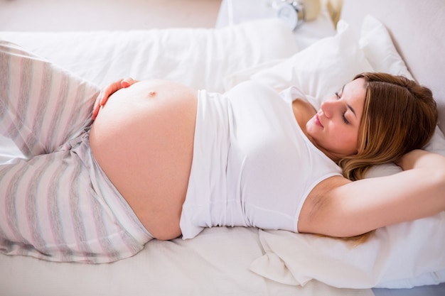 Heureuse femme enceinte allongée sur le lit