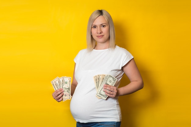 Heureuse femme enceinte avec des avantages pour les femmes enceintes sur un mur jaune. Avantages pour les femmes enceintes