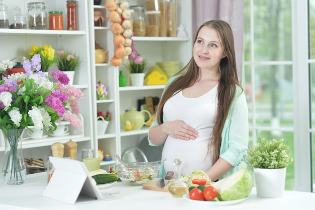 Heureuse femme enceinte cuisinant dans la cuisine