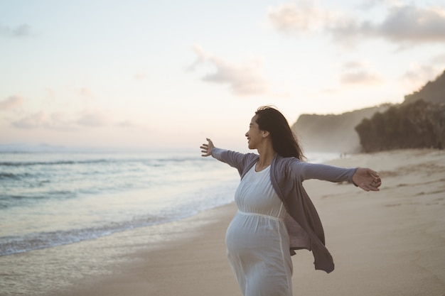 Heureuse femme enceinte debout sur la plage