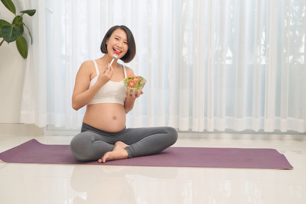 Heureuse femme enceinte, manger une salade de légumes