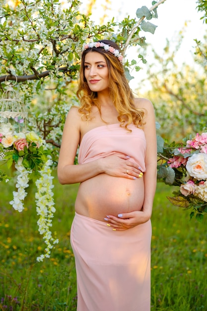 Heureuse femme enceinte en robe rose regardant la femme enceinte au lever du soleil