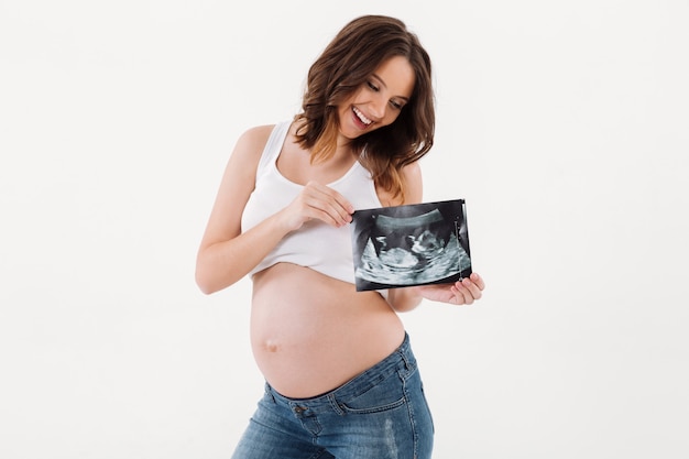 Heureuse femme enceinte tenant l'échographie d'un bébé.