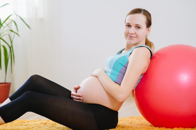 Heureuse femme enceinte tenant pour le ventre et se détendre