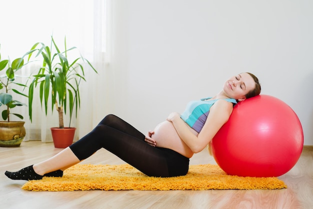 Heureuse femme enceinte tenant pour le ventre et se détendre