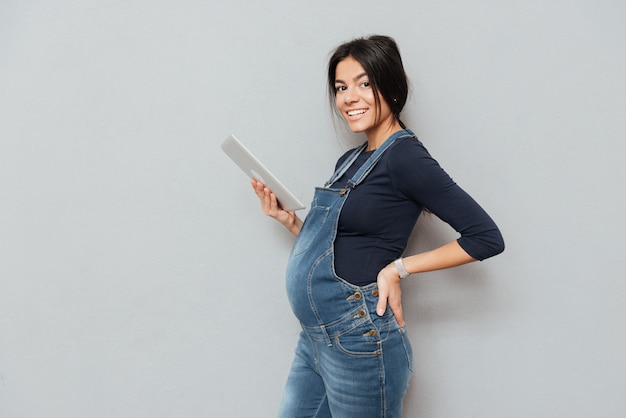 Heureuse femme enceinte tenant une tablette PC