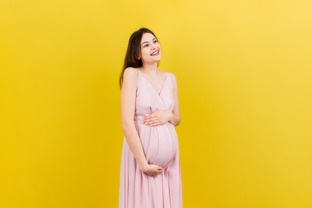 Heureuse femme enceinte touchant son abdomen sur fond coloré La future mère porte des sous-vêtements blancs Attend un bébé Espace de copie