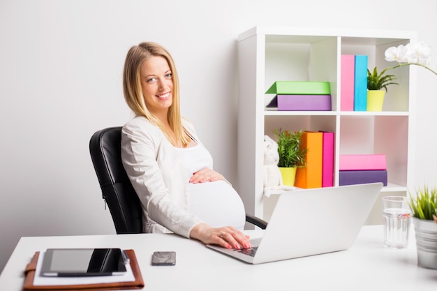 Heureuse femme enceinte travaillant au bureau