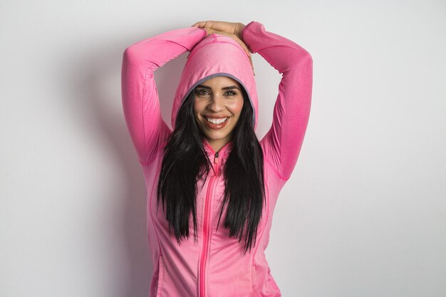Heureuse femme ethnique en tenue de sport levant les mains sur la tête