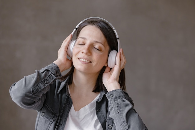 Heureuse femme européenne dansant devant le miroir femme dans des écouteurs blancs se passe de la musique et