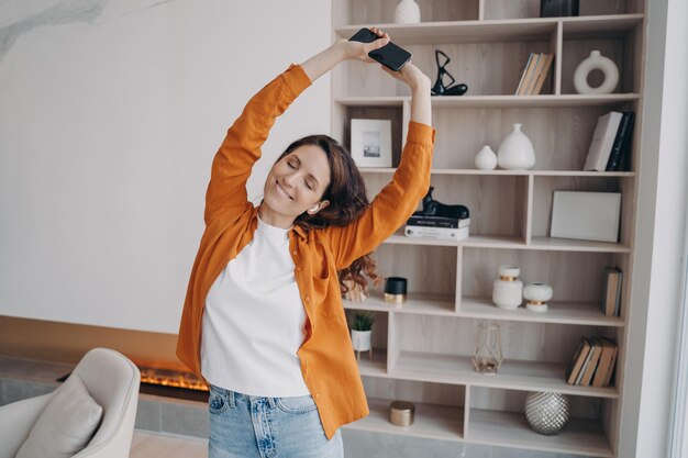 Heureuse femme européenne danse seule à la maison Détente du week-end et expression de l'émotion