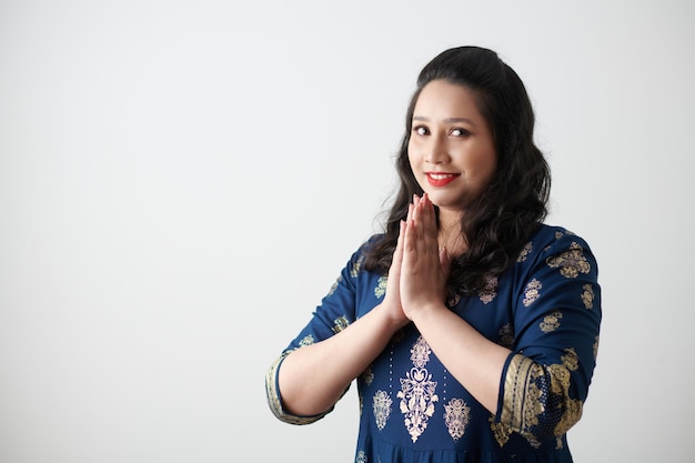 Heureuse femme faisant un geste de namaste lors de l'accueil isolé sur blanc