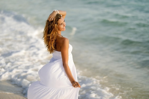 Heureuse femme féminine en robe d'été profitant de l'été au bord de la mer