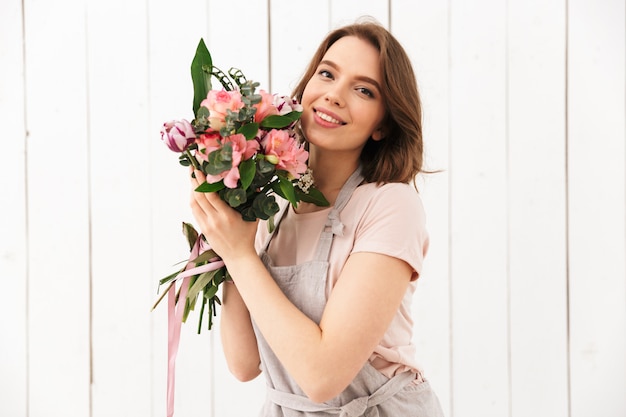 Heureuse femme fleuriste debout avec des fleurs