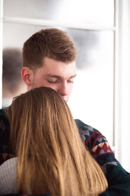 Heureuse femme habillée en pull pose sa tête sur l'épaule de l'homme