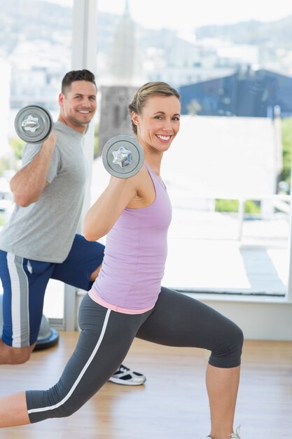 Heureuse femme et homme exerçant avec haltères