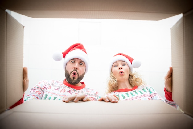 Heureuse femme et homme regardant dans la boîte. Un drôle de couple surpris déballer la boîte-cadeau de Noël. Concept de vacances de Noël. Vue en contre-plongée.