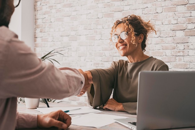 Heureuse femme et homme signant un accord main dans la main Femme d'affaires et client au bureau fermant le contrat avec un sourire Confiance et concept d'entreprise