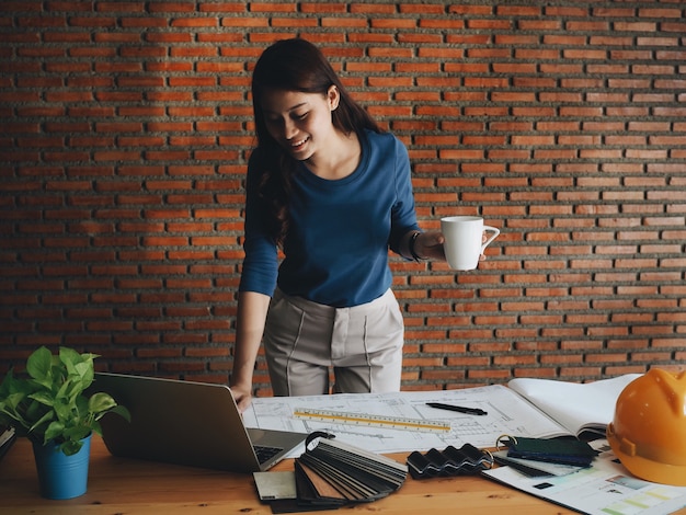 Heureuse femme d'ingénierie, boire du café au bureau.