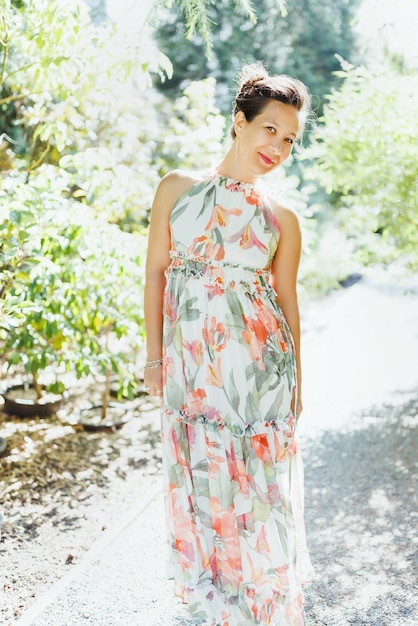 Heureuse femme japonaise multiraciale en robe maxi florale romantique dans le parc d'été