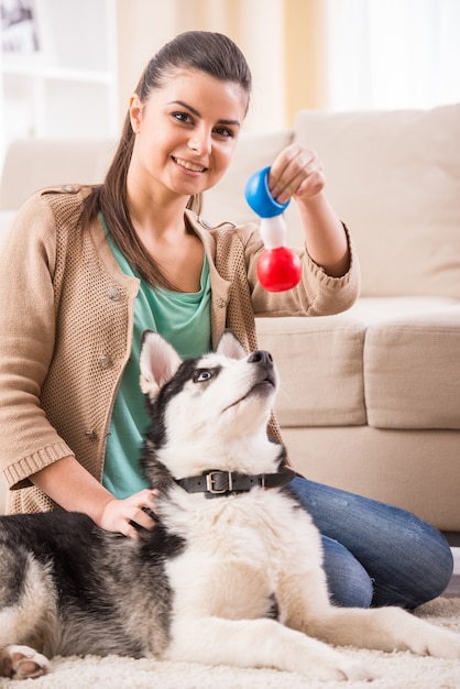 Heureuse femme joue avec son chien à la maison.