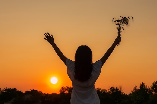 Heureuse femme levant les mains sur le ciel coucher de soleil profitant de la vie et de la nature Silhouette de fille au soleil