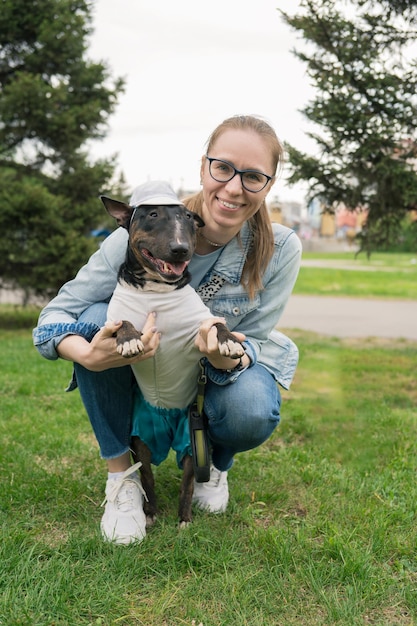 Heureuse femme marchant avec bull terrier dans le parc