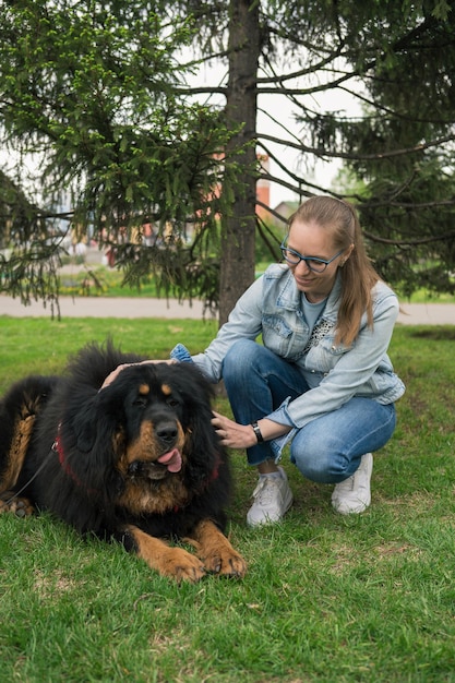 Heureuse femme marchant avec le dogue tibétain dans le parc