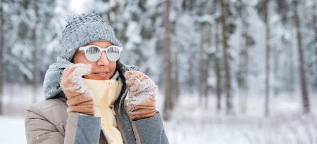 Heureuse femme marchant à l'extérieur par une journée d'hiver enneigée. Modèle féminin vêtu de poudrerie grise s'amusant