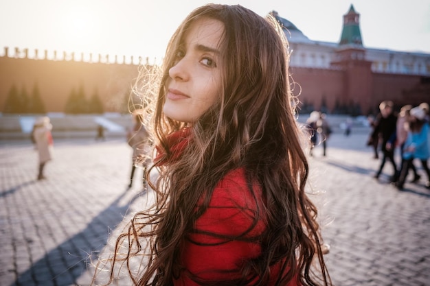 Heureuse femme marchant en manteau rouge sur la place rouge à Moscou Temps froid entre l'hiver et le printemps, le gel et le soleil