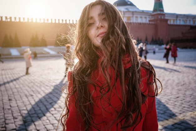 Heureuse femme marchant en manteau rouge sur la place rouge à Moscou Temps froid entre l'hiver et le printemps, le gel et le soleil