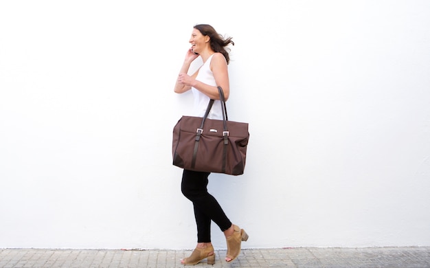 Heureuse femme marchant avec sac et téléphone portable