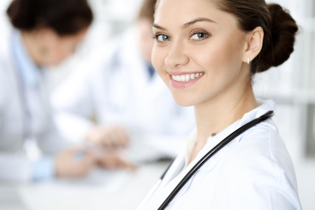 Heureuse femme-médecin souriante assise et regardant la caméra lors d'une réunion avec le personnel médical. Notion de médecine.