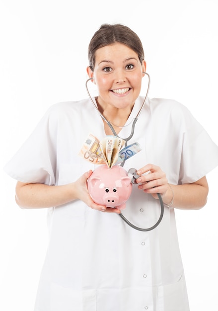 Heureuse femme médecin avec la tirelire pleine d&#39;argent